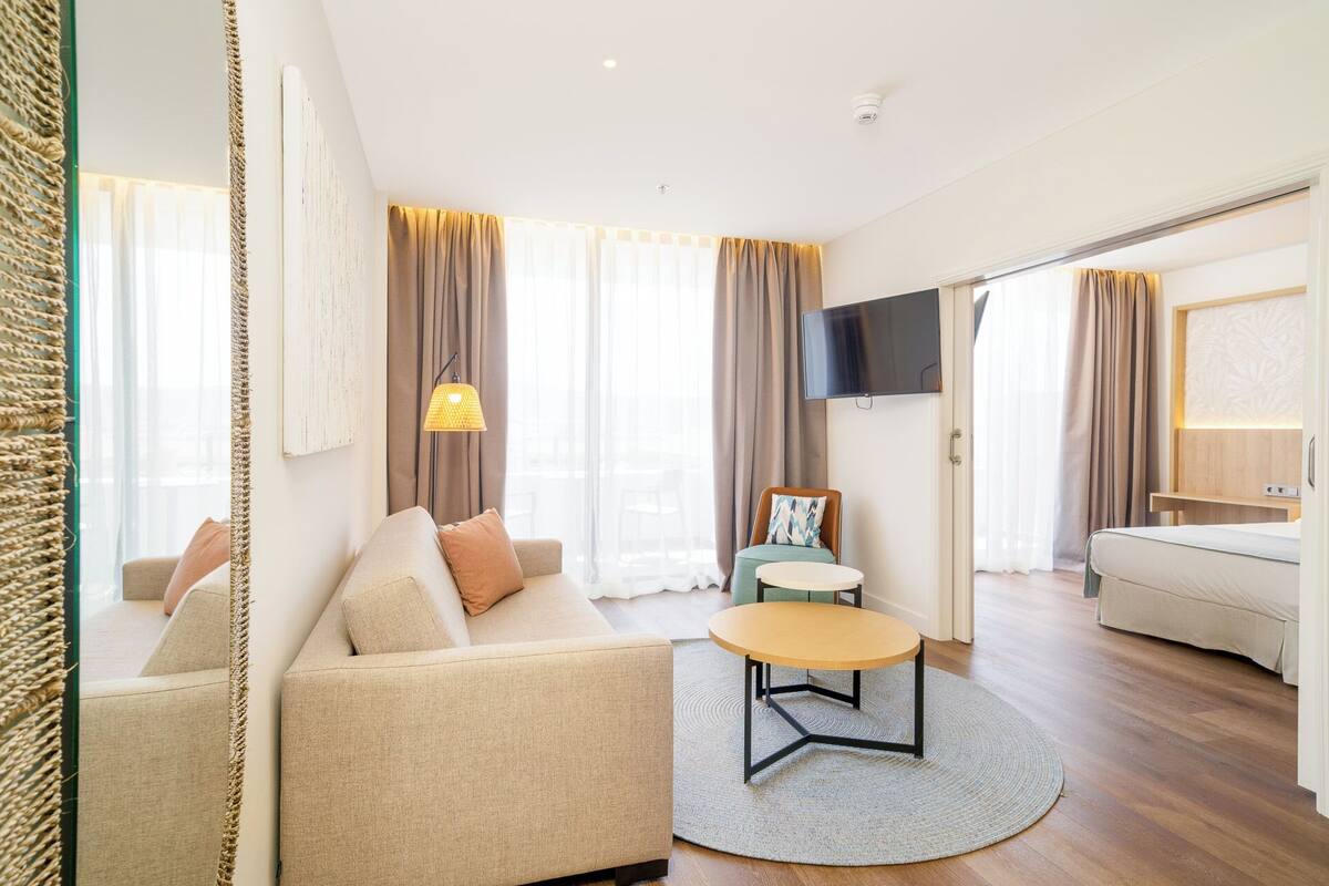 A modern living room with a sofa, a round coffee table, and a TV mounted on the wall.