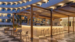 A modern hotel lobby with a bar area, seating, and a checkered floor.