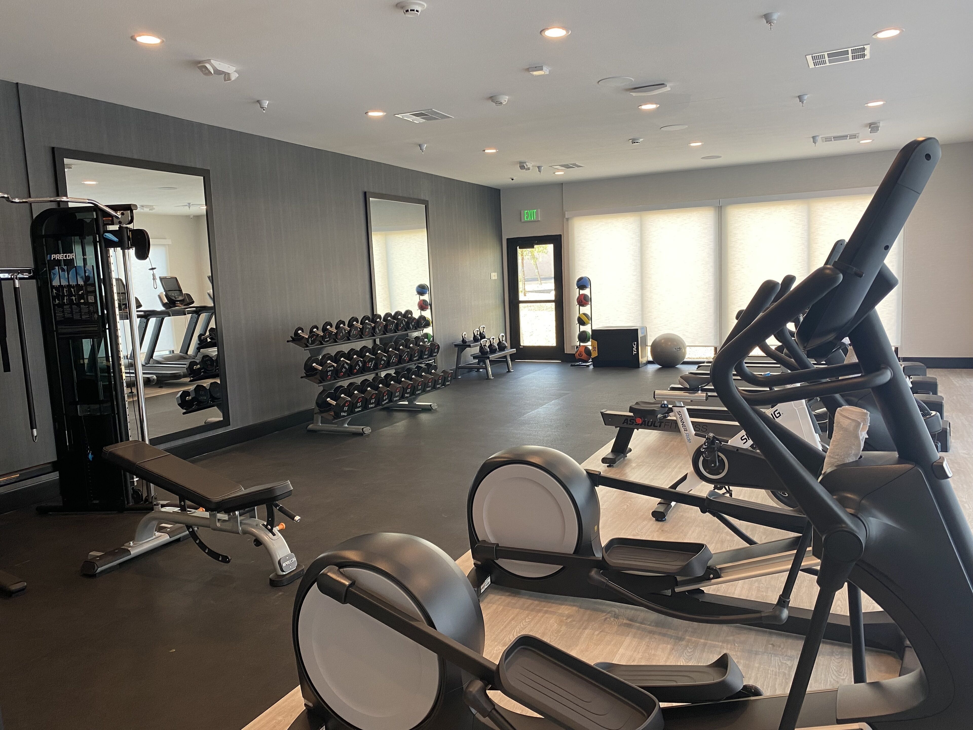 A gym with treadmills, weight machines, and dumbbells.