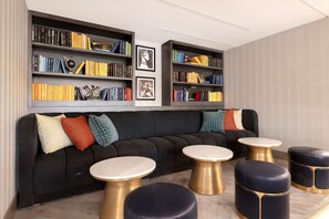 Een moderne woonkamer met een hoekbank, meerdere boekenkasten en ronde salontafels.