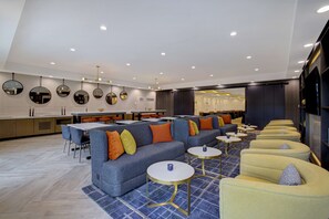 Een moderne hotellobby met een zithoek, een bar en een receptiebalie.