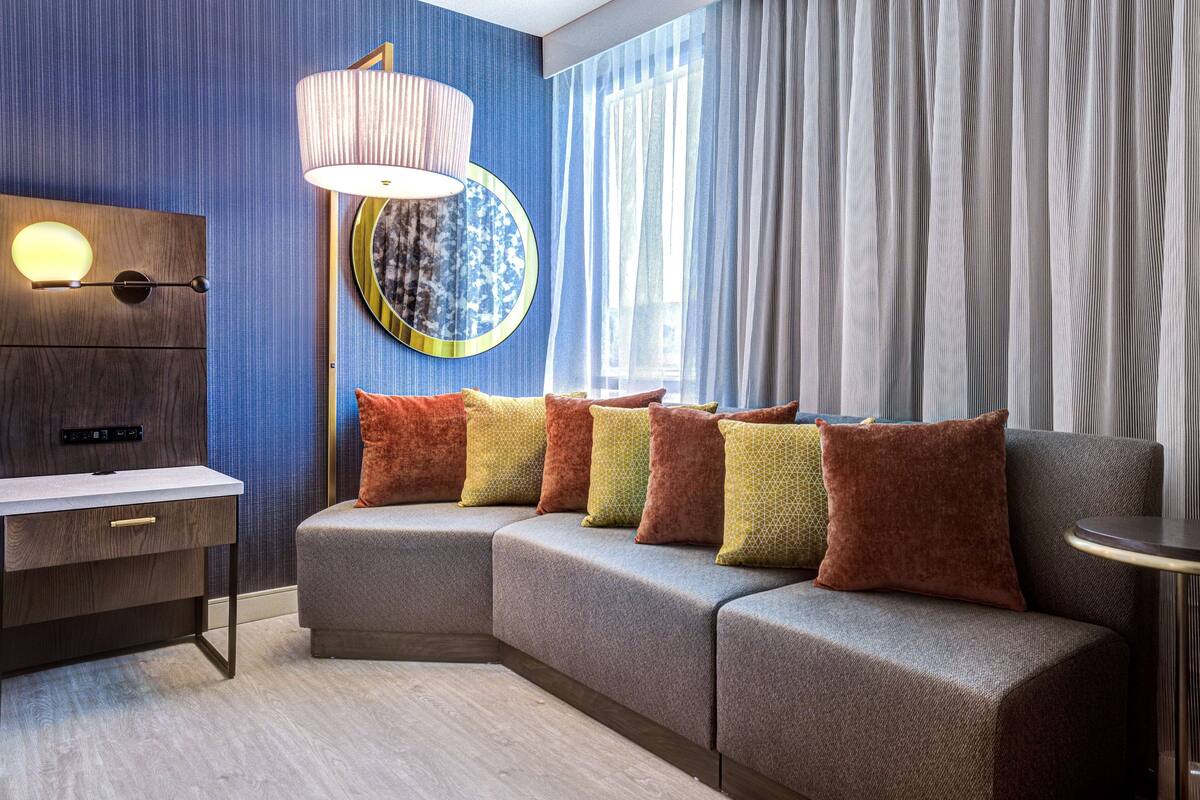 A modern living room with a sectional sofa, a desk, and a lamp.