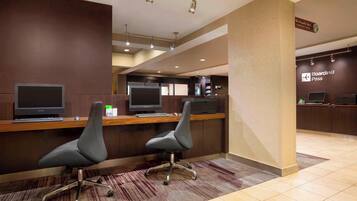 A check-in counter with two computer monitors, a reception desk, and a sign for the Starbucks coffee shop.