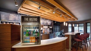 Un bistró moderno con mostrador de madera, un expositor refrigerado para bebidas y una pizarra de menú.