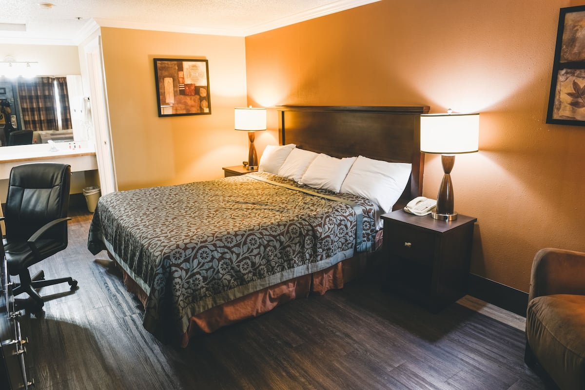 A hotel room with a bed, two bedside lamps, a desk with a chair, and a telephone.