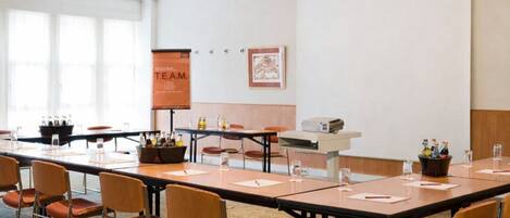A conference room with a long table, chairs, a projector, and a banner.