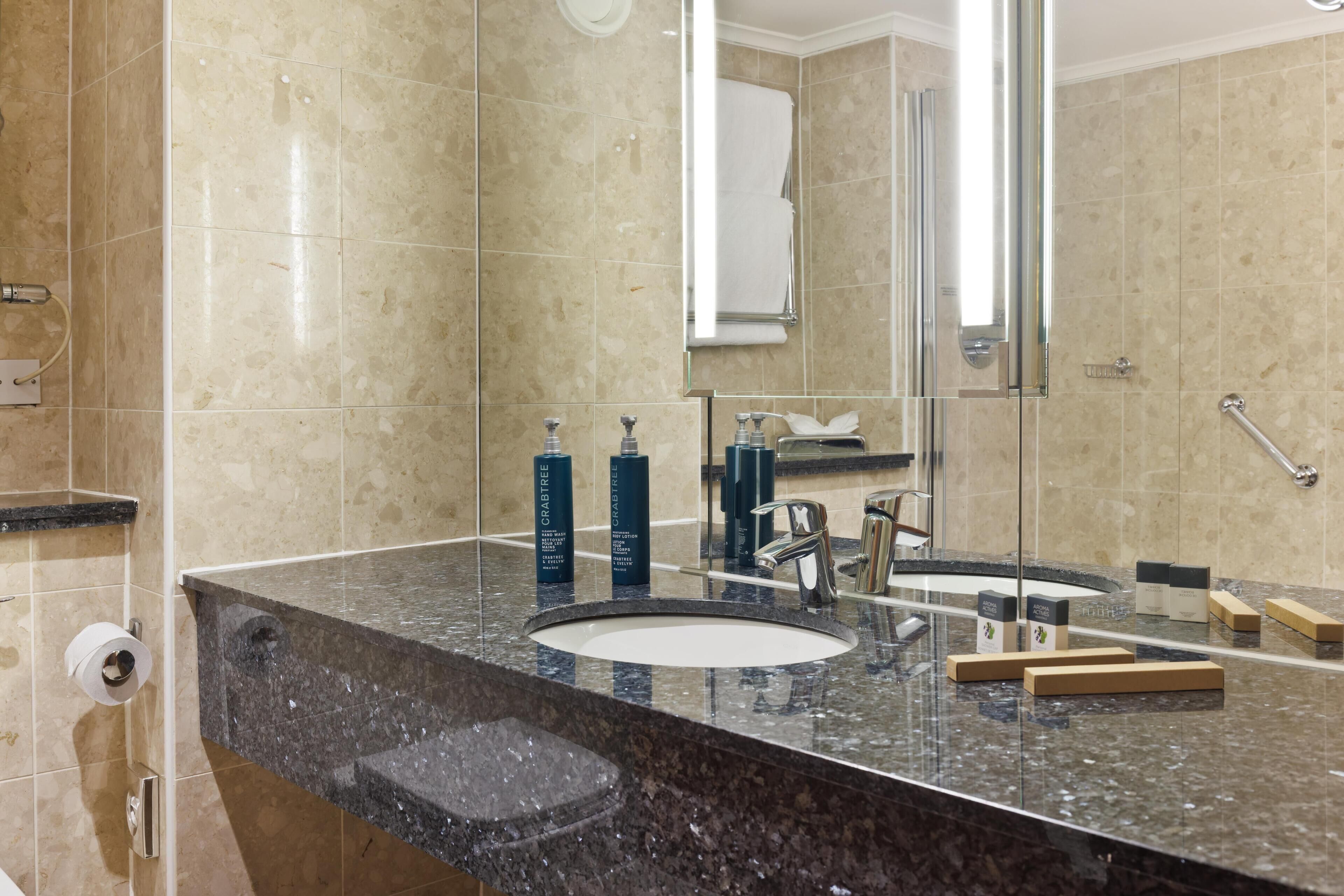A bathroom with two sinks, a large mirror, and toiletries on the counter.