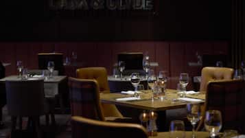 A restaurant interior with tables set for dining, a sign reading 'CASK & CLYDE,' and a dark, moody ambiance.