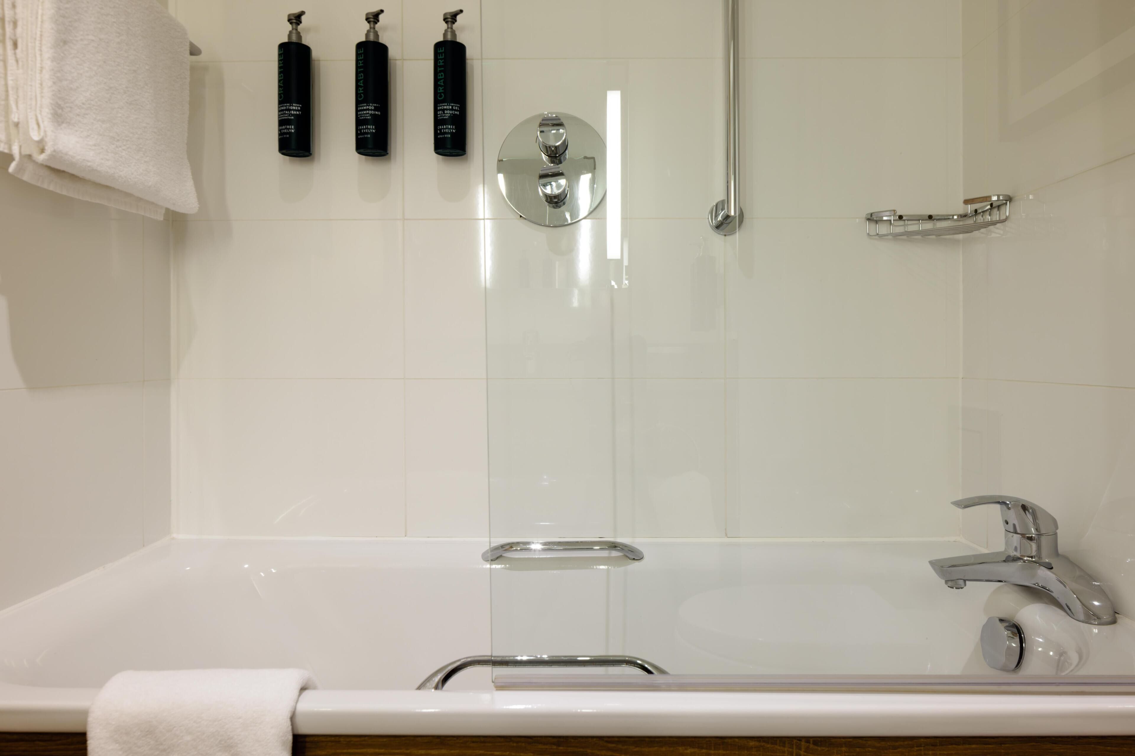 Un baño moderno con bañera, ducha y cabina de ducha con paredes de vidrio.