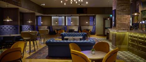 A modern interior with a blue sofa, yellow chairs, and a bar area.