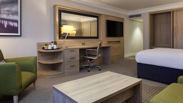 Ein Hotelzimmer mit Bett, Schreibtisch, Stuhl, großem Spiegel, Fernseher und Kleiderschrank.