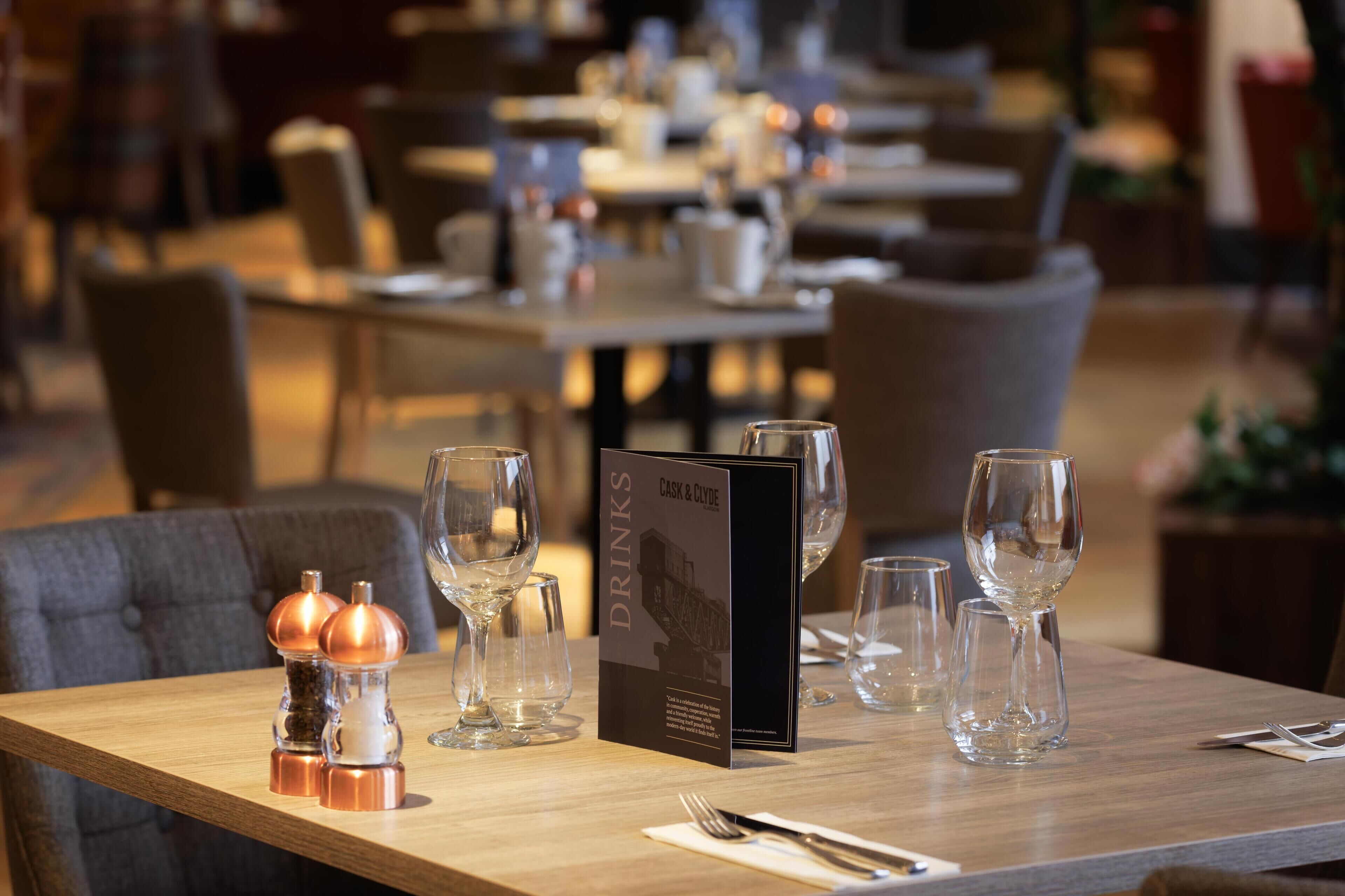 A restaurant table with a menu, salt and pepper shakers, and wine glasses.