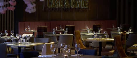 Un restaurante con mesas dispuestas para comer, un letrero que dice 'CASK & CLYDE' y un interior oscuro.