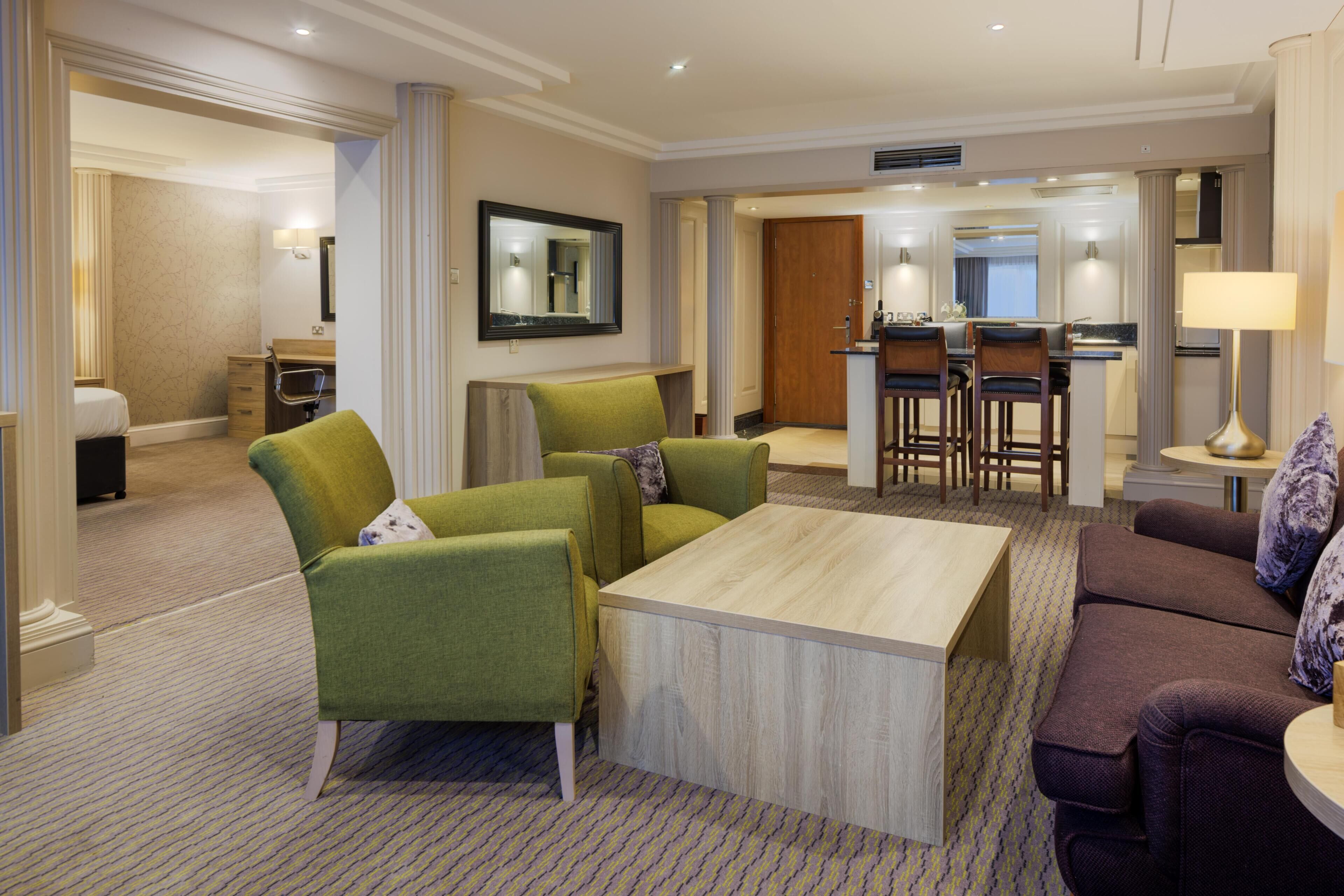 A hotel room with a living area, a dining table, and a kitchen area.