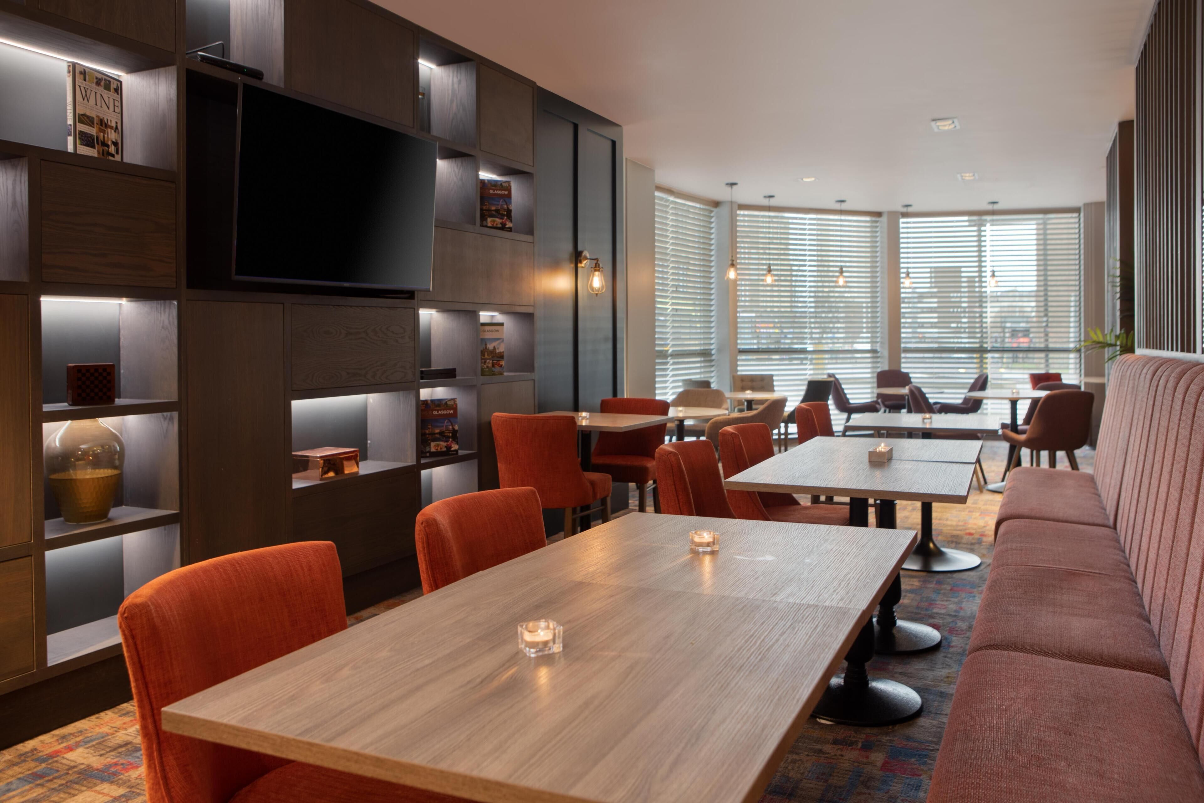 A modern interior with a dining area, sofas, and a TV mounted on a wall.