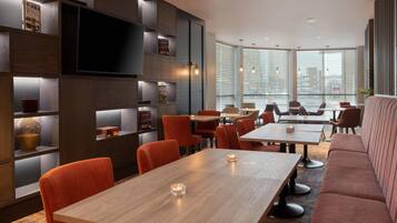A modern interior with a dining area, sofas, and a TV mounted on a wall.