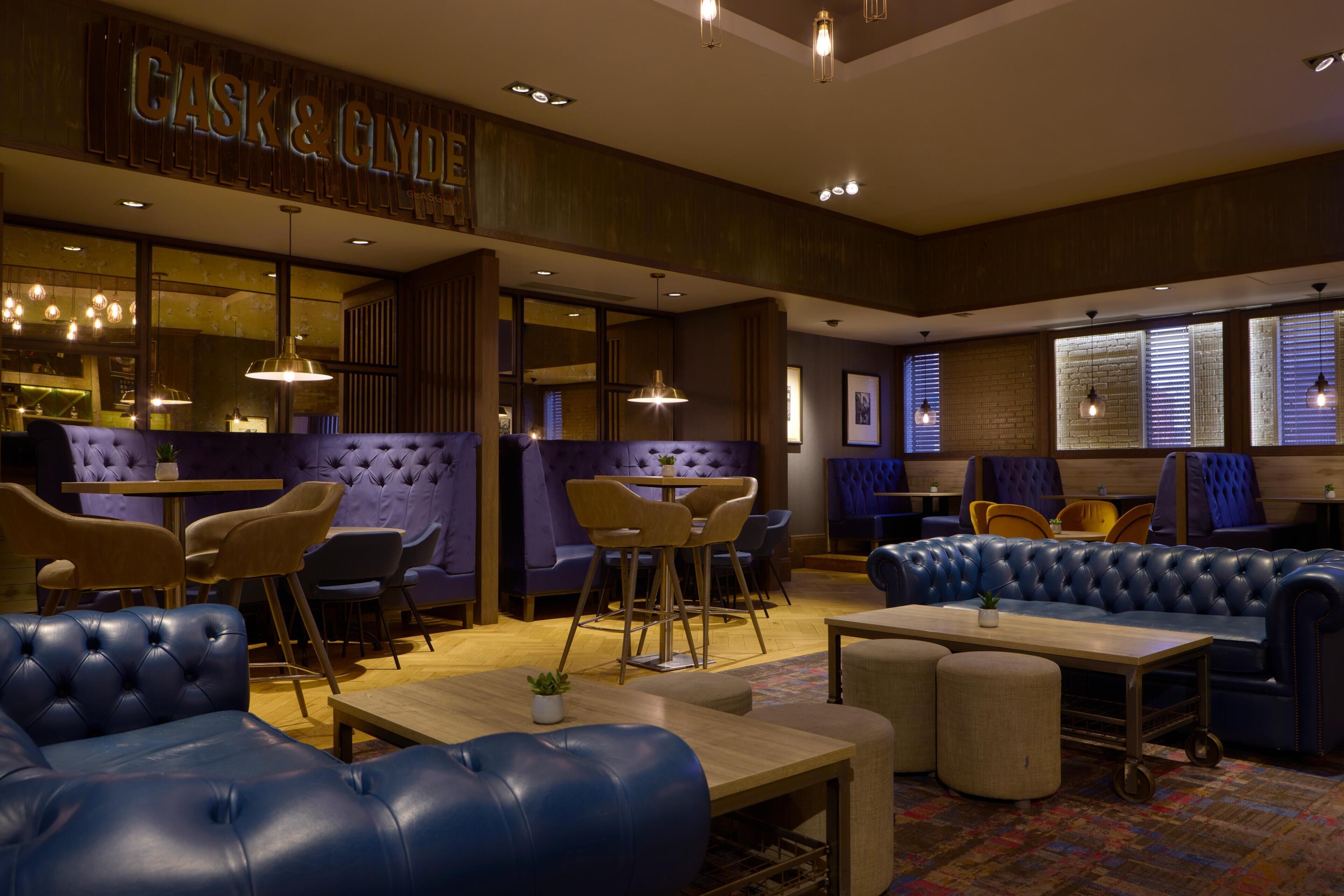 A modern interior with leather sofas, wooden tables, and pendant lighting.