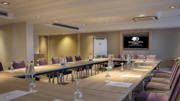 A conference room with a long table, chairs, and a screen displaying the DoubleTree by Hilton logo.