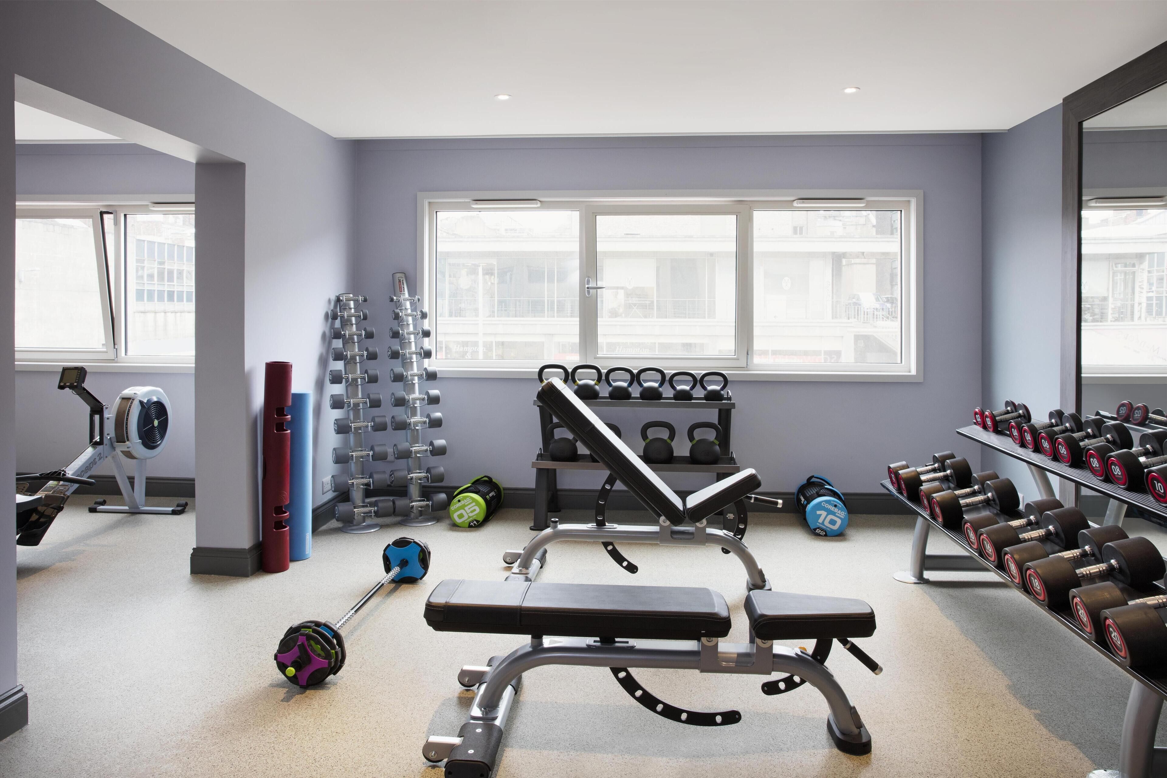 A gym with weightlifting equipment, a bench, and dumbbells.