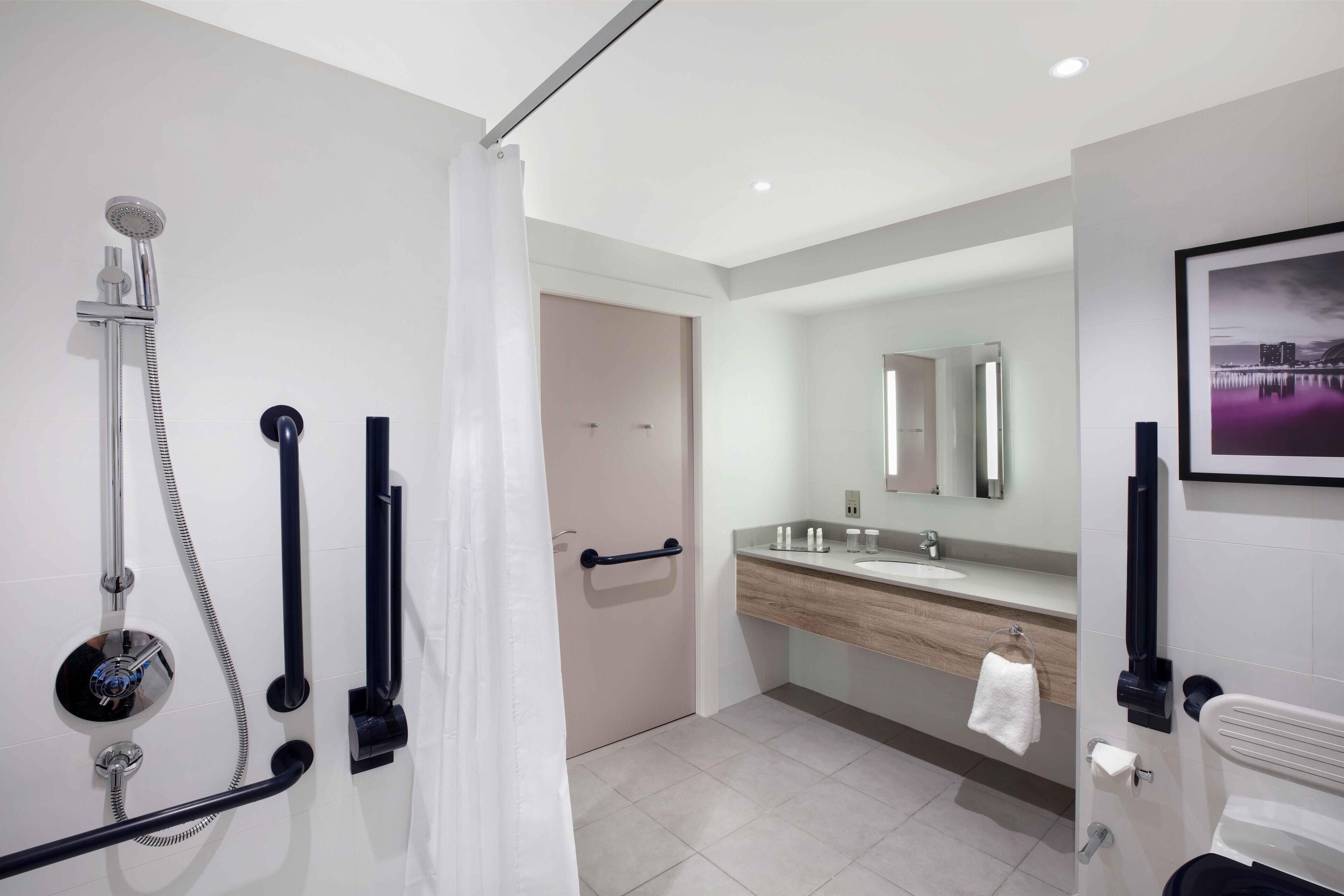 A modern bathroom with a shower, a sink, a mirror, and a towel rack.
