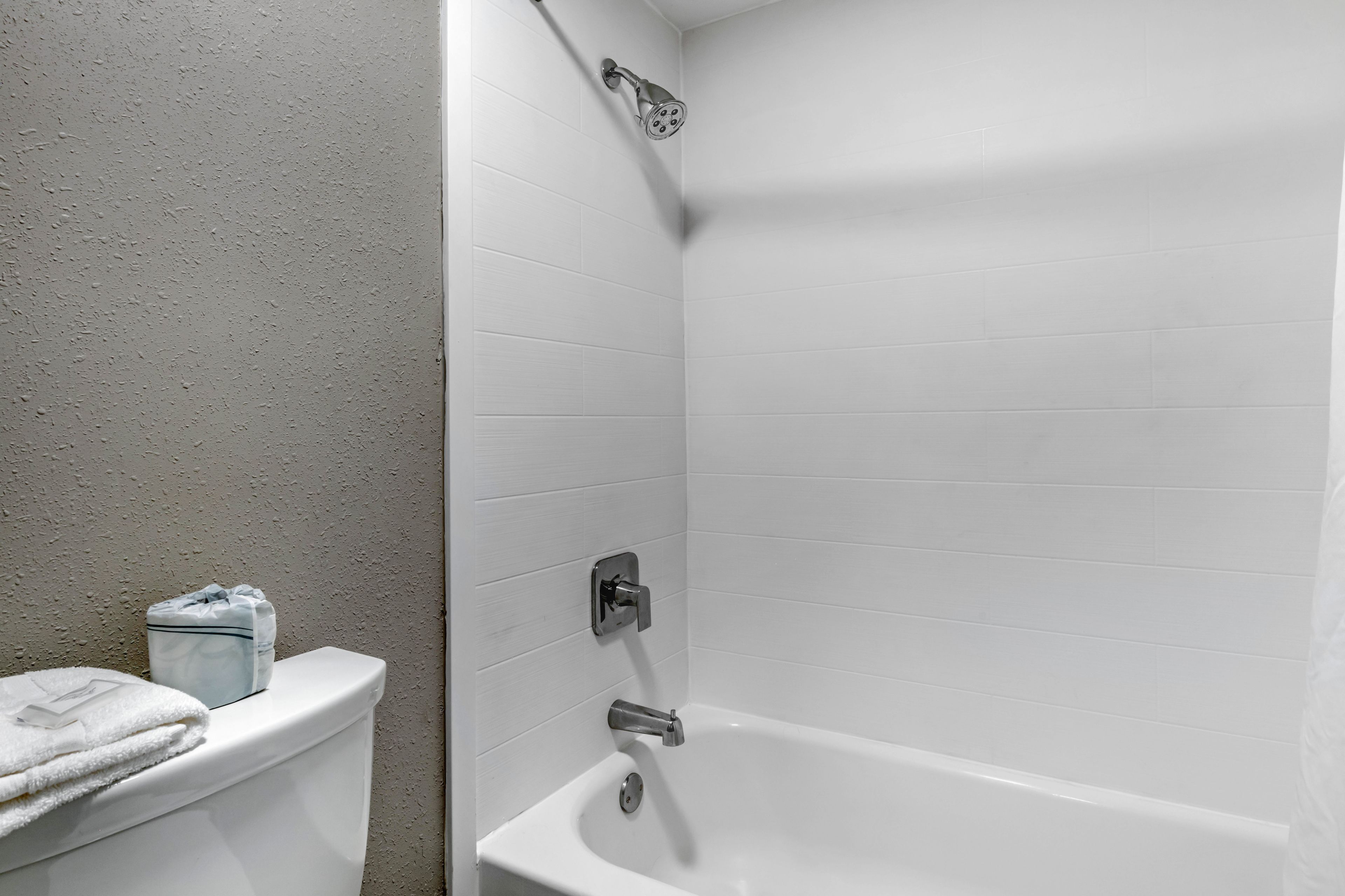 A bathroom with a white bathtub, a toilet, and a towel rack.