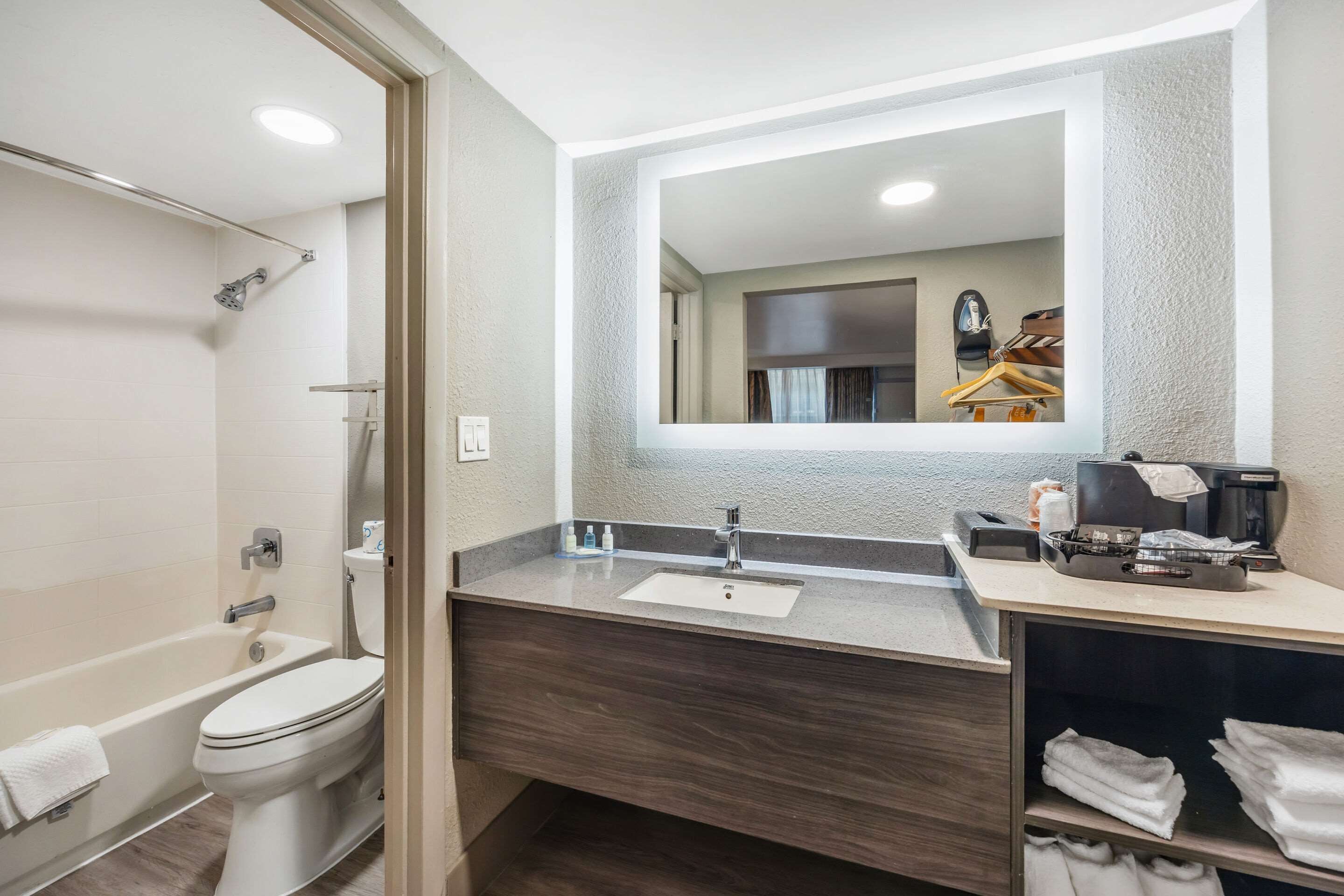 A modern bathroom with a bathtub, toilet, vanity with a sink, and a mirror.