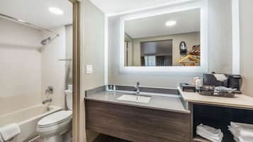 A modern bathroom with a bathtub, toilet, vanity with a sink, and a mirror.