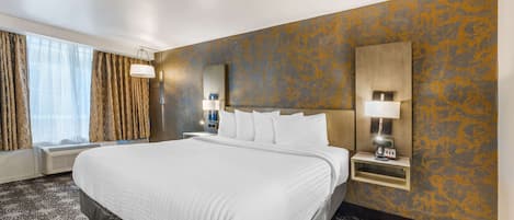 Habitación de hotel con una cama grande, una mesita de noche con lámpara, una ventana con cortinas y una pared con diseño decorativo.