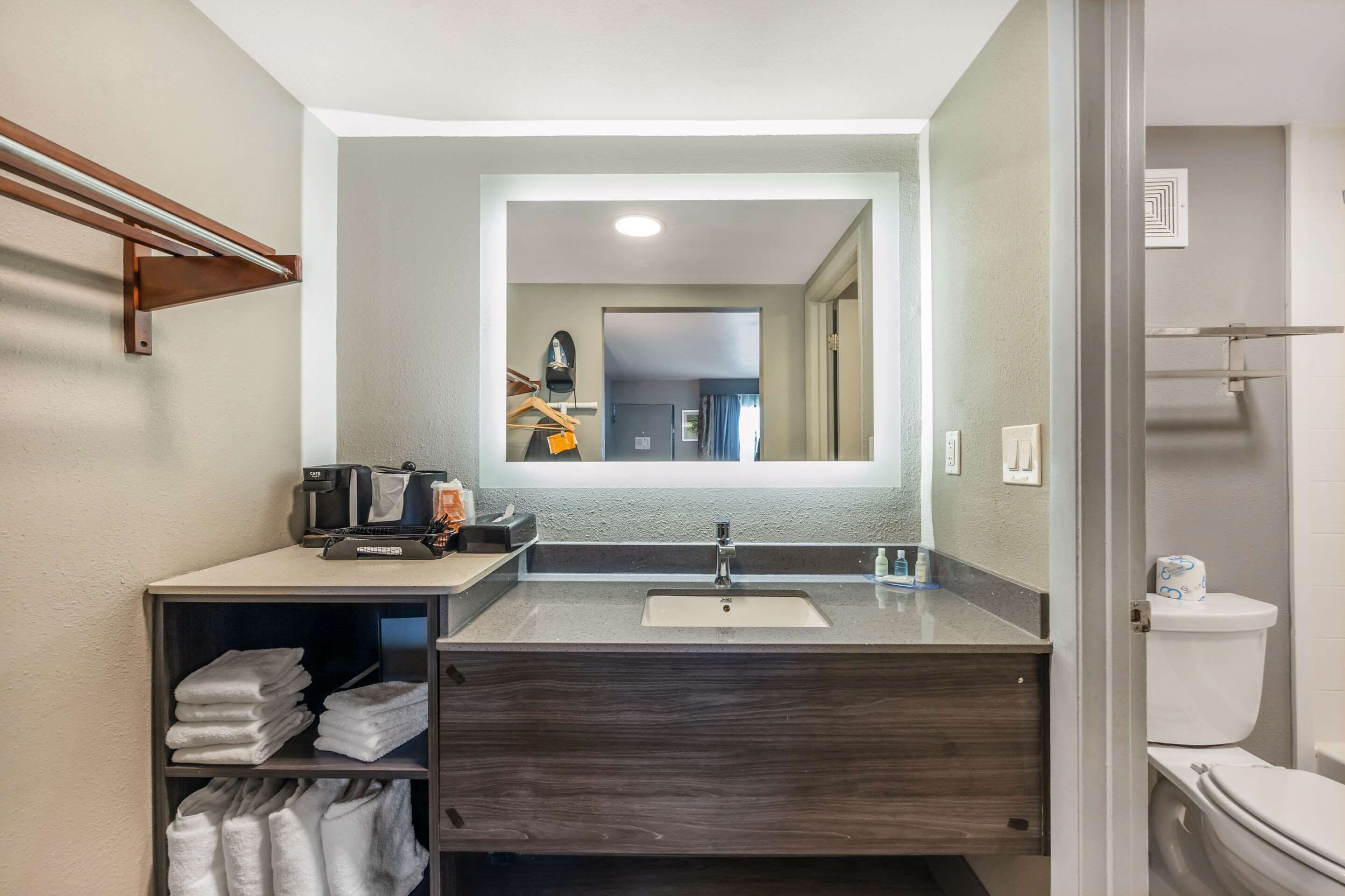 A modern bathroom with a dark wood vanity, a sink, and a mirror.