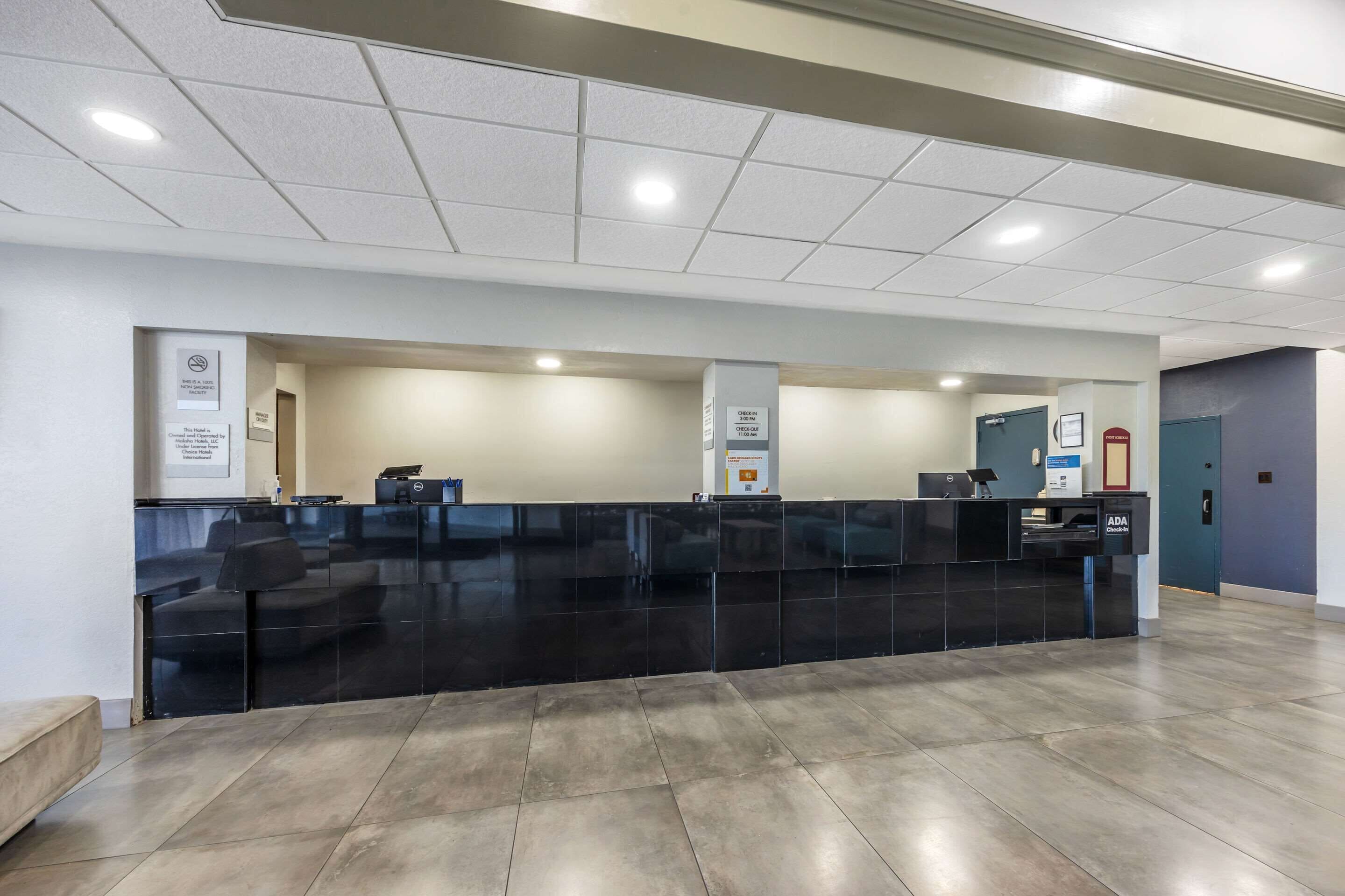 A reception area with a black reception desk, a digital screen, and a counter.