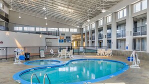 An indoor swimming pool with two separate sections, surrounded by a tiled floor and equipped with safety railings.