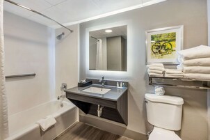 Un baño con bañera, lavamanos, espejo, inodoro y toallero.