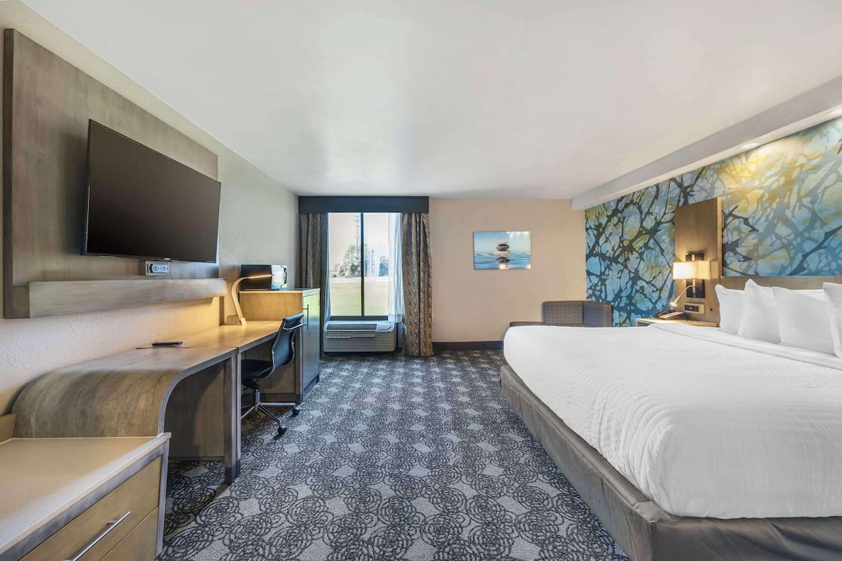 Une chambre d’hôtel équipée d’un lit, d’un bureau, d’une chaise, d’un téléviseur à écran plat et d’une grande fenêtre.