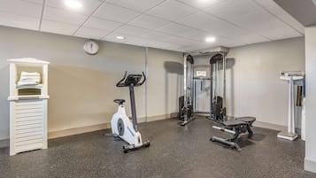 A gym with a stationary bike, a bench press, and a weight rack.