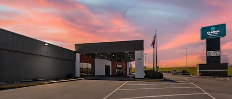 Een hotelingang met een parkeerplaats, een bord met Clarion Inn & Suites en een Amerikaanse vlag.