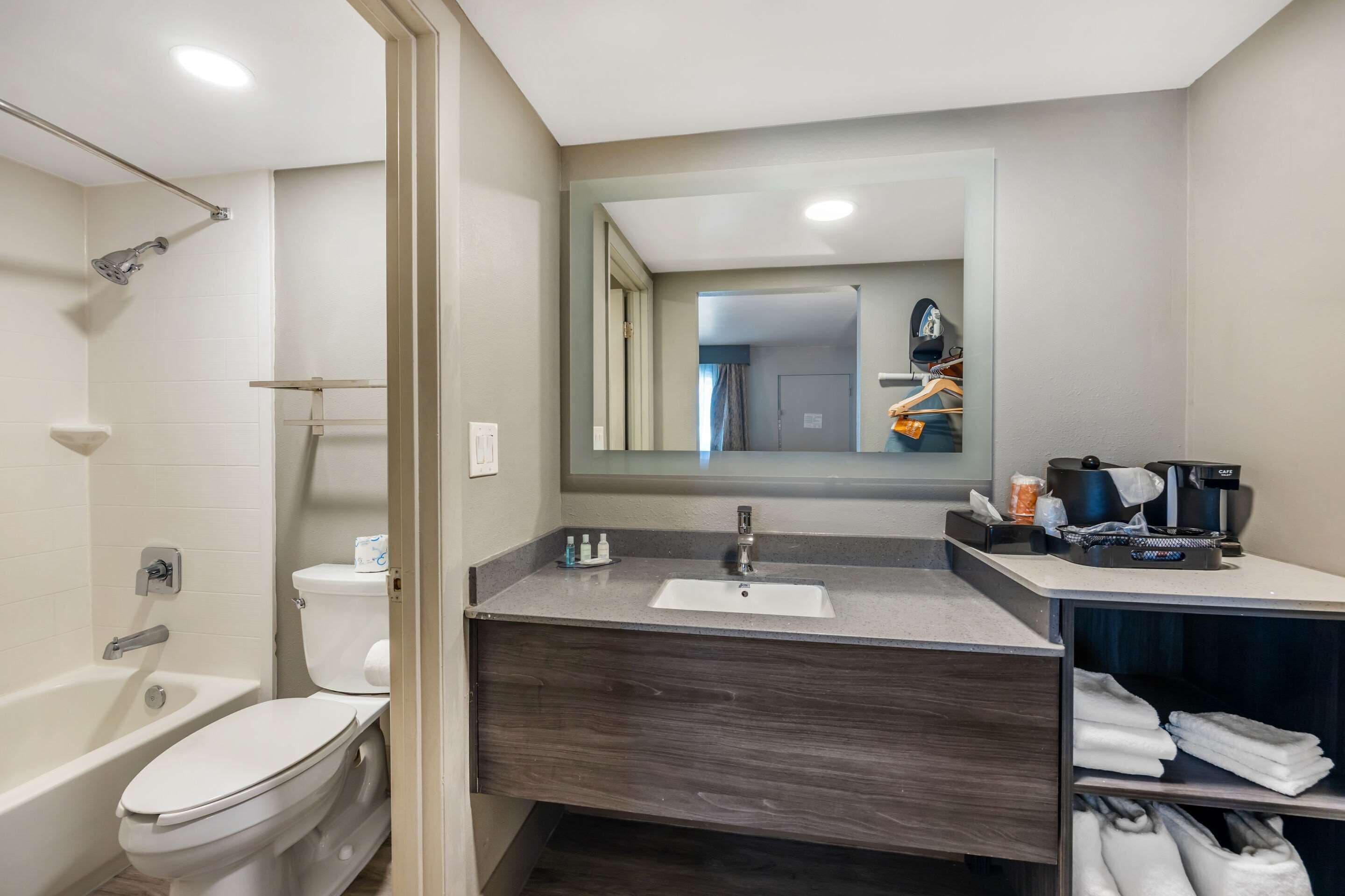 Une salle de bain moderne équipée d’une baignoire, de toilettes et d’un meuble-lavabo avec un évier et un miroir.