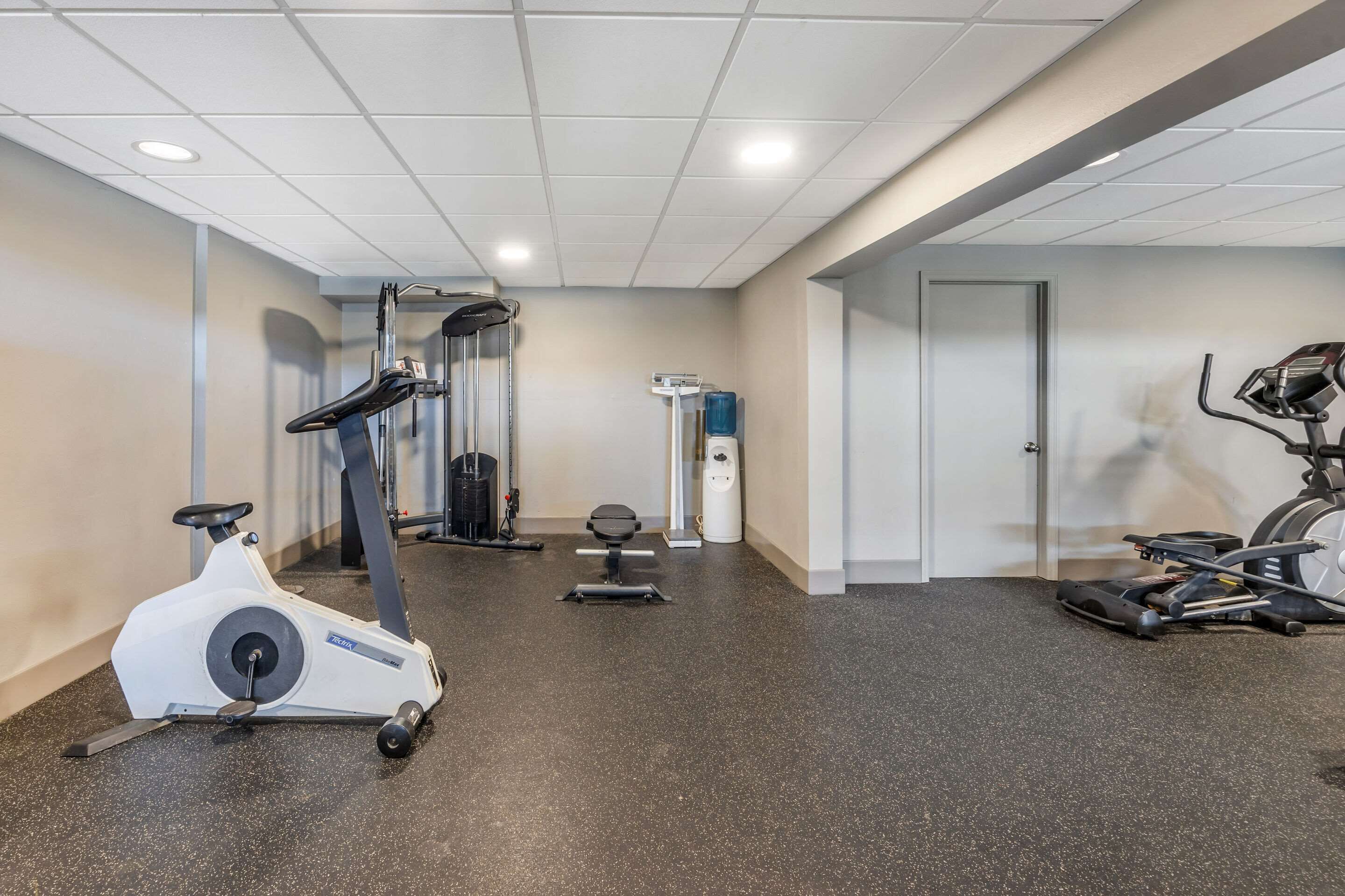 Une salle de sport équipée de vélos d’appartement, d’un tapis de course et d’appareils de musculation.