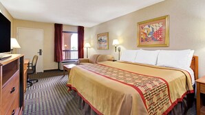 A hotel room with a large bed, a desk, a chair, a television, and two lamps. - Days Inn by Wyndham Wilson (Wilson)