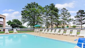 A swimming pool with white lounge chairs and a blue umbrella. - Days Inn by Wyndham Wilson (Wilson)