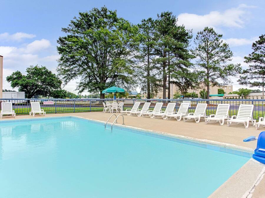 Ein Pool mit weißen Liegestühlen und einem blauen Sonnenschirm.