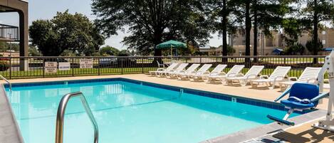A swimming pool with lounge chairs and a lifeguard stand.
