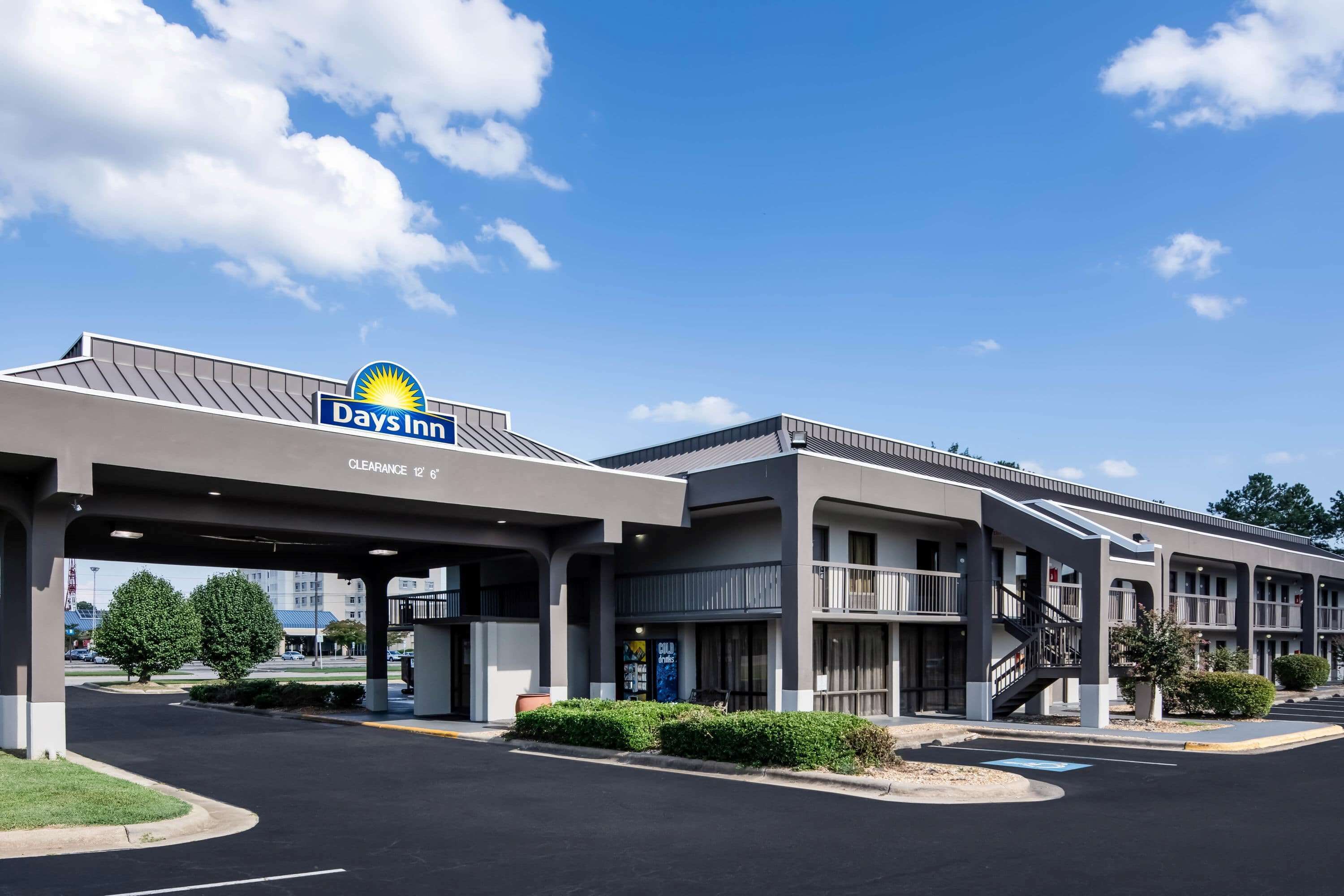 A Days Inn hotel with a clear sky, parking lot, and a sign indicating a clearance of 12'6".