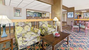 A hotel lobby with a sofa, a wooden table, and a patterned carpet. - Days Inn by Wyndham Wilson (Wilson)