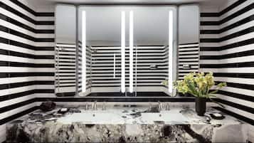 A modern bathroom with a black and white striped tile wall, a large mirror, and a marble sink with two faucets.