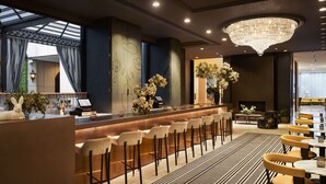 A modern bar area with a high ceiling, a chandelier, and a patterned floor. - Park Lane New York (New York)