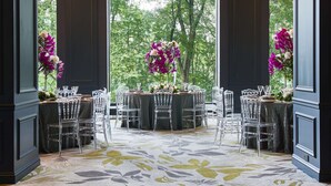 An indoor dining area with a chandelier, clear chairs, and floral centerpieces. - Park Lane New York (New York)