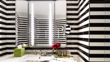 A bathroom with a black and white striped tile wall, a large mirror, a marble sink, and a green soap dish with a red flower.