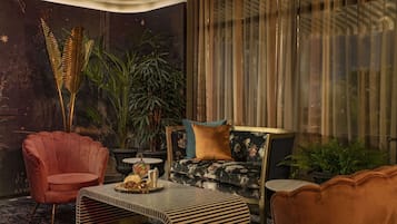 A modern living room with a sofa, armchair, and coffee table, featuring a large plant and decorative items.