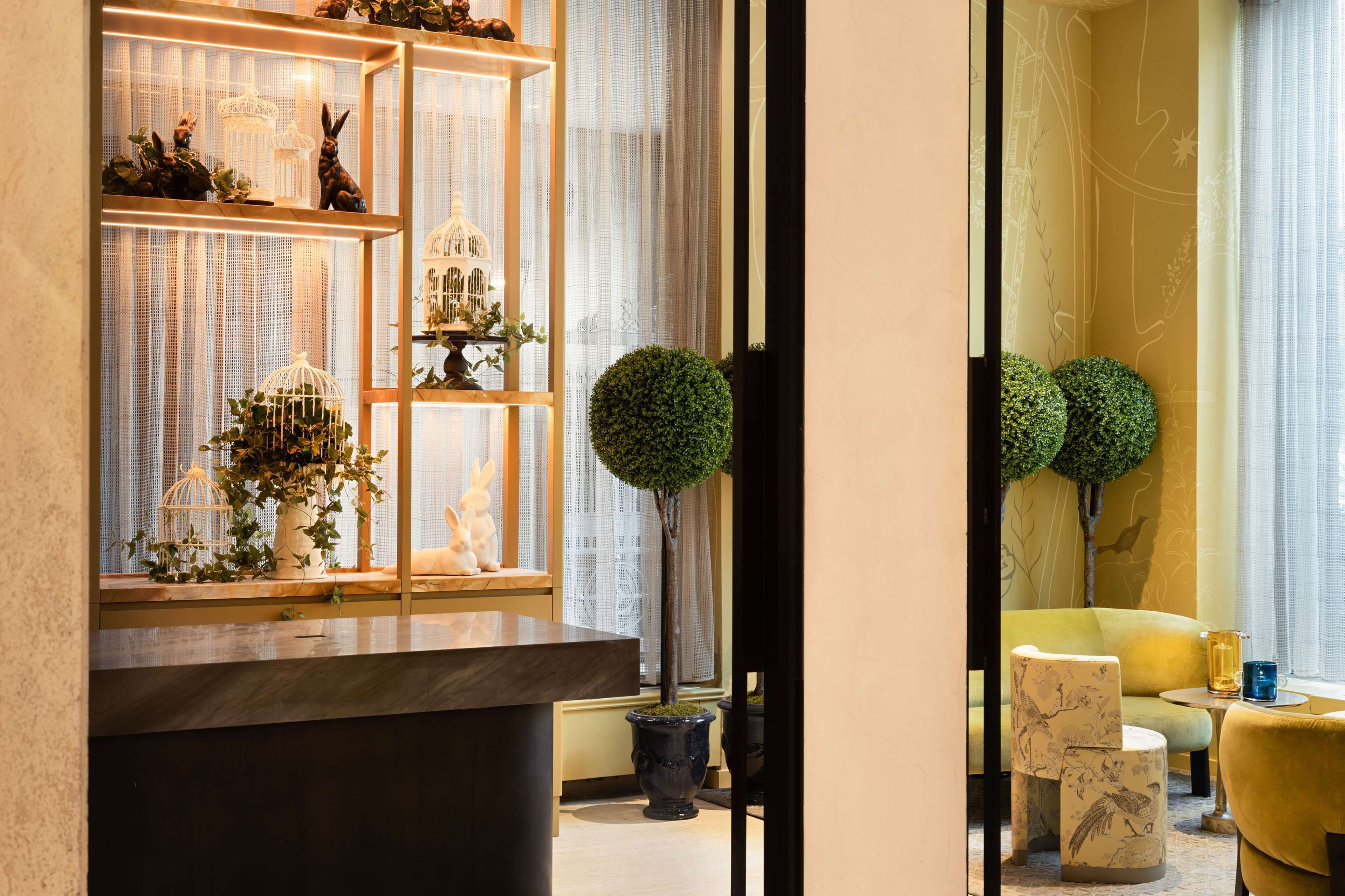 A reception area with a wooden reception desk, a glass display case with decorative items, and a seating area with a yellow sofa and chairs.
