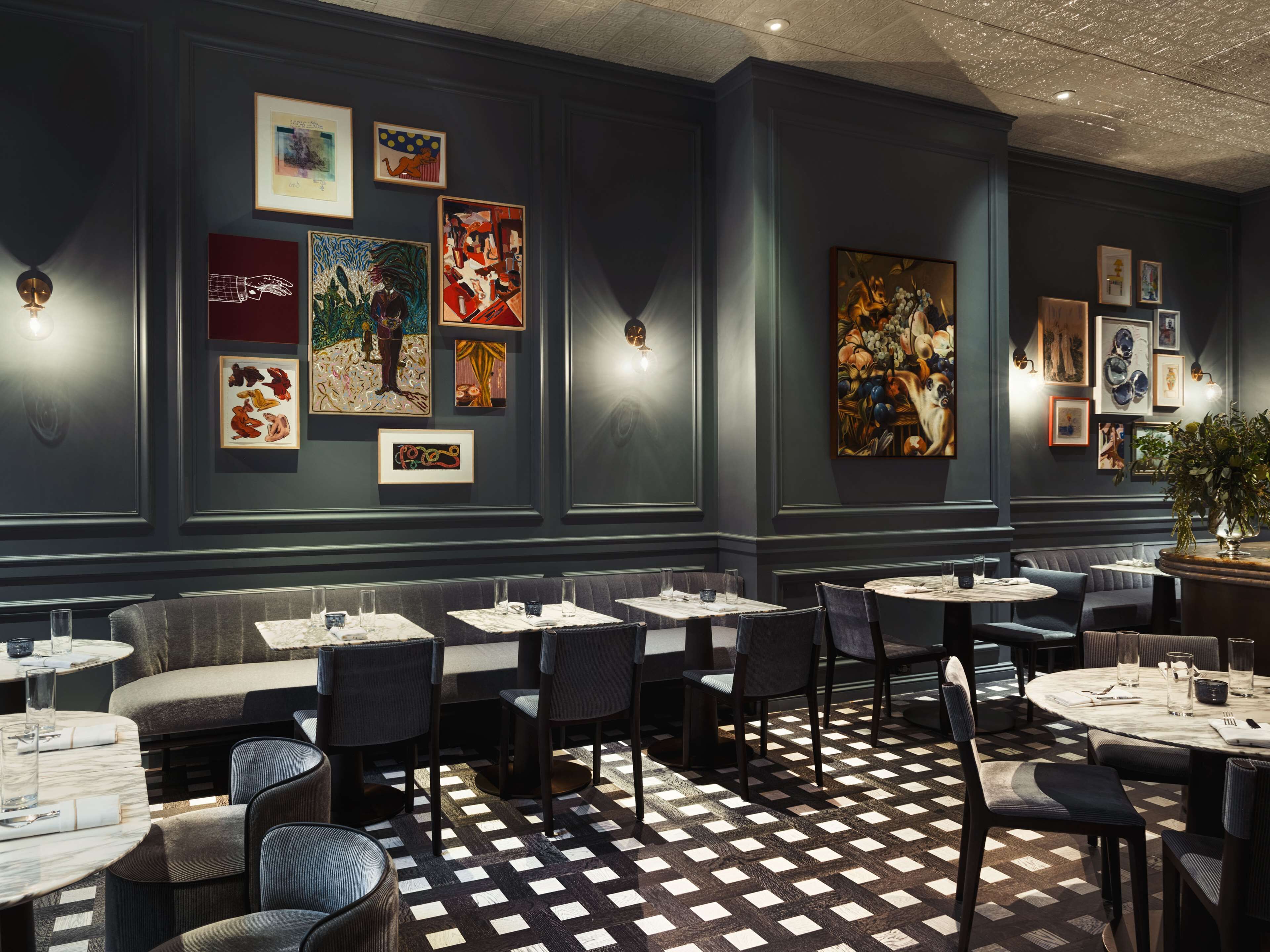 Un restaurant avec un sol à carreaux, plusieurs espaces pour s’asseoir et des œuvres d’art accrochées aux murs.